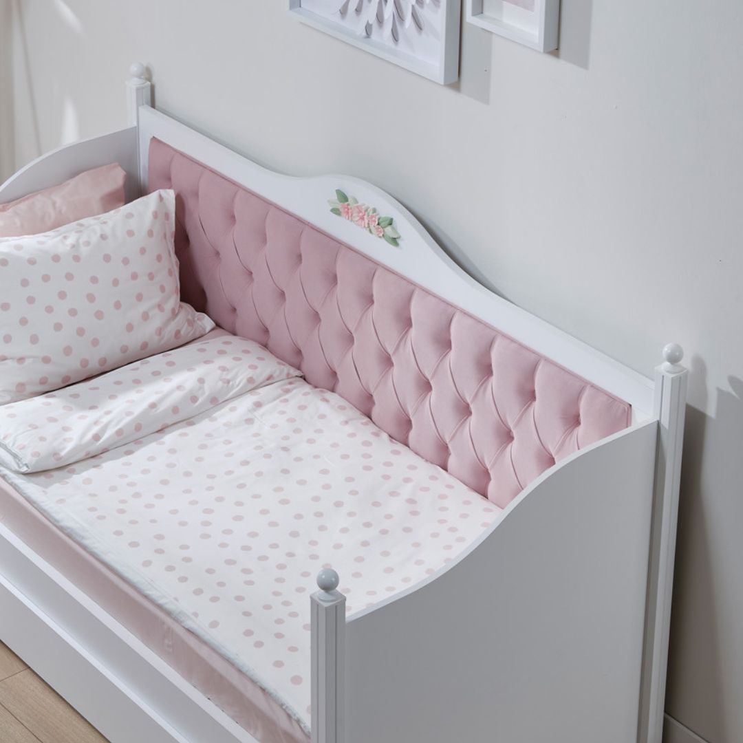 Детско легло Bianca с монтирана розова капитонирана тапицерия по облегалката. Стаята изглежда нежна и уютна, със светли тонове и пастелен текстил.