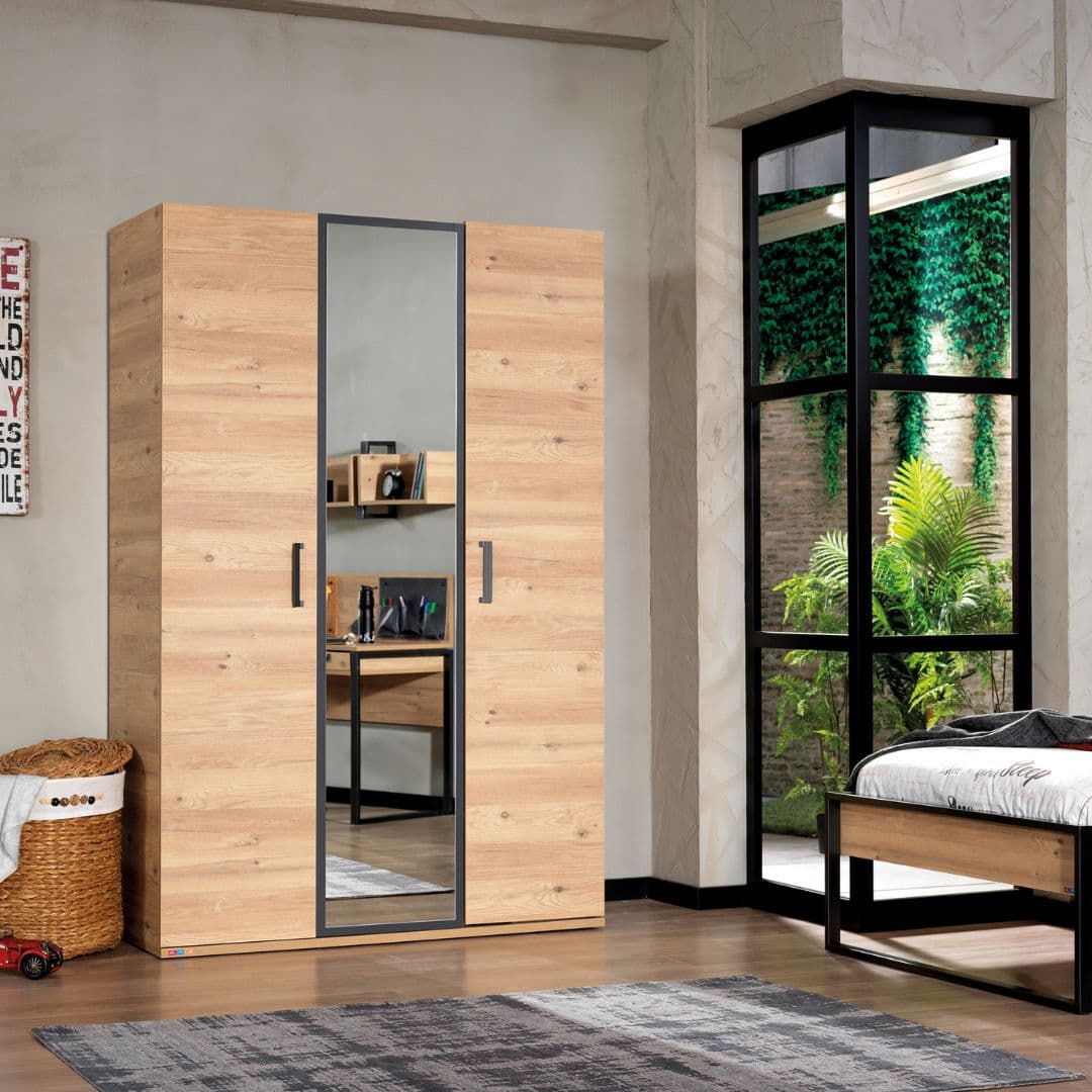 Трикрилен детски гардероб Irony в стая - дървесен декор с централно огледало и тъмни кантове. Стои модерно и прави интериора по-светъл.