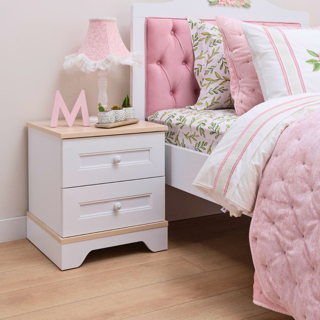 Нощно шкафче Bianca до легло с розова тапицирана табла и мека лампа. Шкафчето стои светло и уютно, с удобен плот за вечерни дреболии.