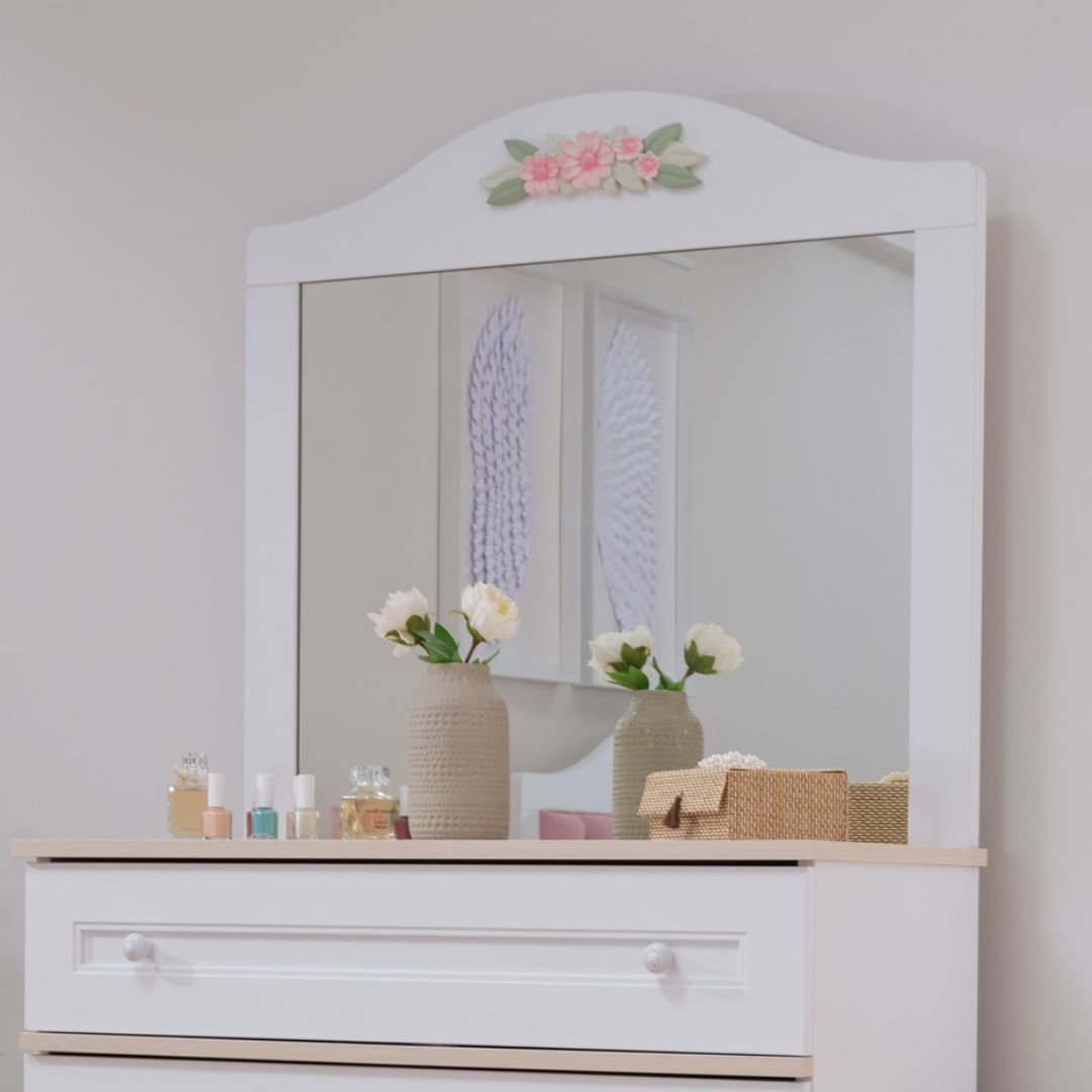 Огледало Bianca, монтирано над детски скрин в светла детска стая. Декоративното цвете добавя нежен акцент и прави къта по-завършен.